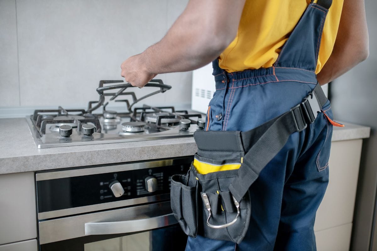 Technician repairing a gas stove in a modern kitchen