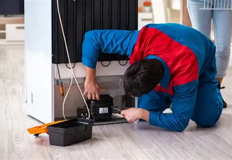 Technician repairing a refrigerator in a kitchen